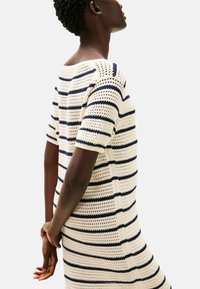 Sukienka dzianinowa w paski z kremowymi i granatowymi poziomymi paskami, krótkimi rękawami oraz luźną teksturą szydełkową z szerokim dekoltem.