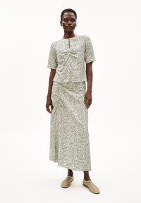 Zweiteiliges Outfit bestehend aus einem kurzen Oberteil und einem langen Rock, beide aus leichtem Stoff mit einem kleinen Blau- und Grünton-Muster. Das Oberteil hat kurze Ärmel und ein Schlüsselaugen-Detail.