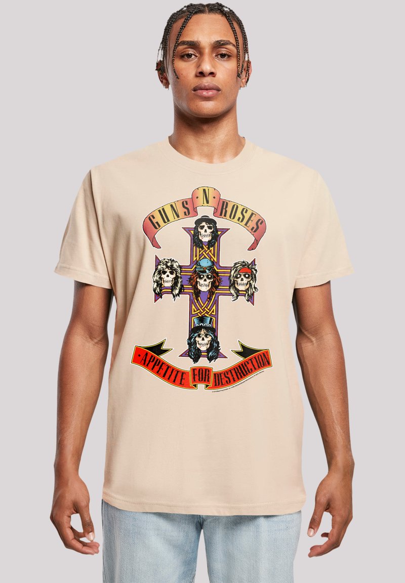 Beige Baumwoll-T-Shirt mit einem Frontgrafikdesign von einem Totenkopf mit gekreuzten Knochen, Text "GUNS N' ROSES" und "APPETITE FOR DESTRUCTION", in kräftigen Farben.