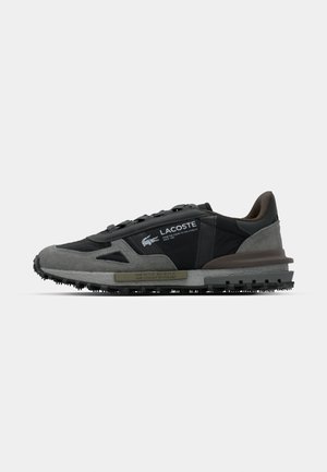 Lacoste sneakers in grijs en zwart. Voorzien van een gestructureerde bovenkant, vetersluiting en rubberen zool met opvallende profielen. Merklogo aan de zijkant.
