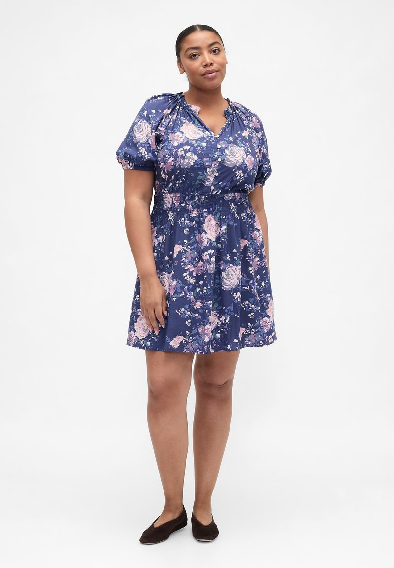 Blumenkleid in Marineblau mit kurzen Puffärmeln, einem V-Ausschnitt und einem gerafften Taillenbund. Mit durchgehendem Muster aus rosa und weißen Rosen.