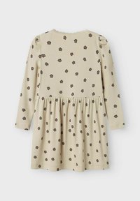 Robe beige à manches longues avec une texture côtelée, ornée d'un motif floral marron foncé, avec une taille froncée et un col en dentelle.