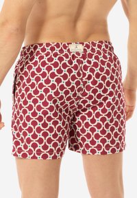 Pantaloni da nuoto con un motivo geometrico in bordeaux, crema e blu, dotati di una cintura elasticizzata e di un piccolo etichetta con logo sul retro.