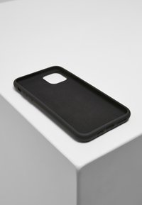 Carcasa neagră pentru telefon cu finisaj mat, având decupaje pentru cameră și butoane, interior texturat și un design subțire, rectangular.