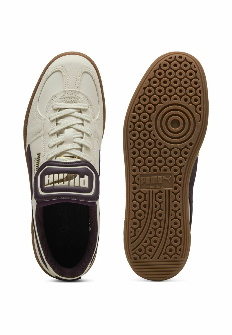 Baskets PUMA avec un upper en cuir crème, des accents violets, un design à lacets et une semelle en caoutchouc à motif. Présente une marque PUMA bien visible.