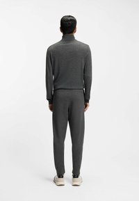 Ciemnoszary, dopasowany top z długim rękawem oraz pasujące do niego spodnie dresowe; gładka faktura, prążkowany kołnierzyk i mankiety, zestawione z jasnymi sneakersami.