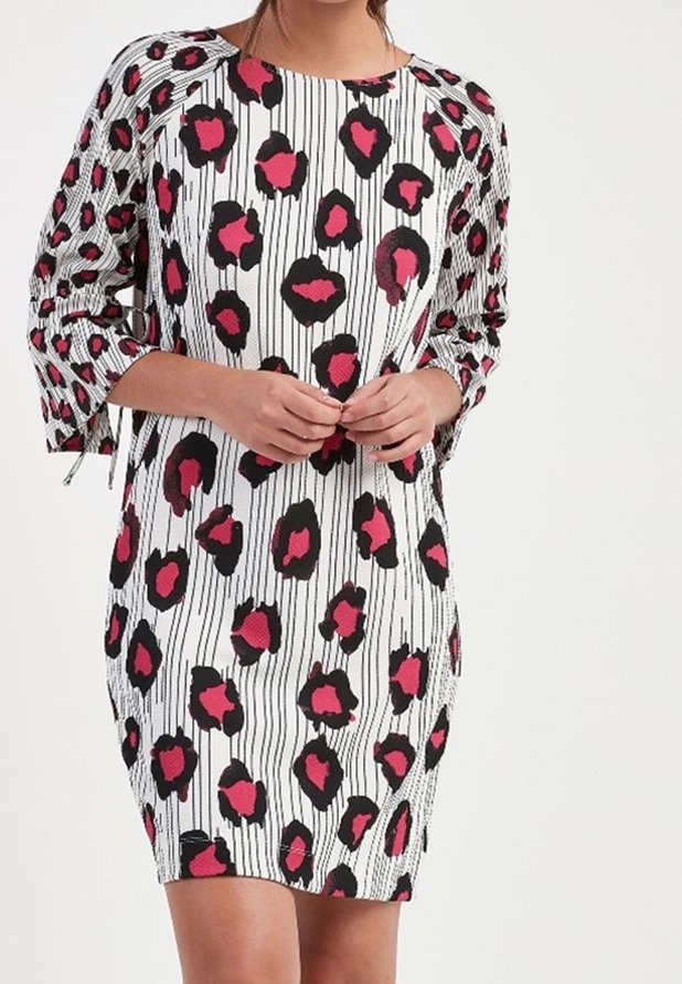 Robe à manches courtes avec une base blanche ornée de rayures verticales noires et de grandes taches de léopard roses et noires, fabriquée dans un tissu lisse.