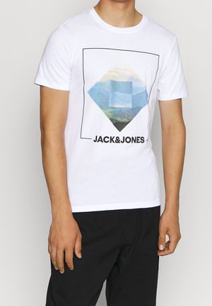 Person iført en hvid T-shirt med korte ærmer med et geometrisk bjergprint og "JACK&JONES" tekst foran.