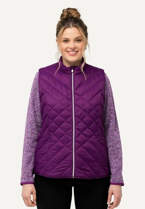 Vesti quilted purppura con colletto alto, cerniera frontale e tasche laterali. Indossato su una maglietta a maniche lunghe testurizzata di una tonalità più chiara di purppura.