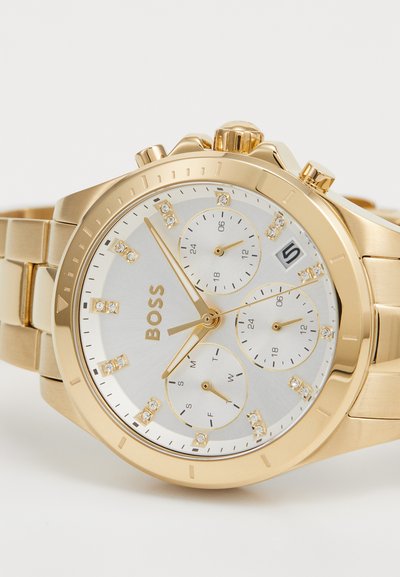 Montre-bracelet chronographe dorée avec un cadran argenté, trois sous-cadrans, marqueurs d'heures en cristal et bracelet doré. Comprend un affichage de la date.