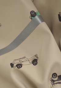 Tissu beige avec des graphiques de voitures noirs et verts ; présente une rayure grise brillante au centre ; texture lisse.