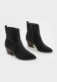 Svarta mockaankelboots med spetsig tå, sidoglidning och en måttlig klack. Slät yta med en snygg design.