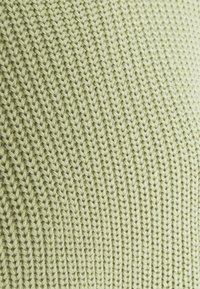 Tissu tricoté vert clair présentant un motif côtelé texturé avec des points entrelacés, offrant un aspect doux et lisse.