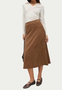 Brun mocka maxikjol med en åtsittande midja och utsvängd nederdel, kombinerad med en ljusbeige långärmad skjorta och svarta leopardskinn flats.