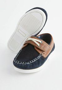 Marineblaue Wildlederschuhe mit braunen Lederakzenten, weißer Gummisohle und gathered stitching. Verfügt über einen Klettverschluss und dekorative Schnürsenkel.