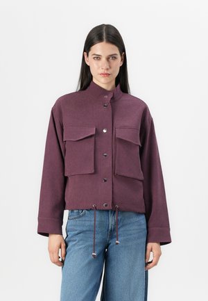 Purple cropped jacket with a high collar, two front pockets, silver snap buttons, and drawstring hem; made from a soft, textured fabric.