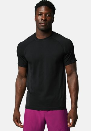 Schwarzes athletisches T-Shirt mit kurzen Ärmeln, figurbetontem Design und strukturierten Seitenpanelen. Das Material wirkt feuchtigkeitsableitend und atmungsaktiv.