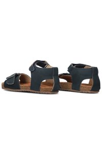 Zwarte leren sandalen met open zijkanten, verstelbare strapsluiting en een gestructureerde zool. Bevat een kurken binnenzool en rubberen buitenzool.