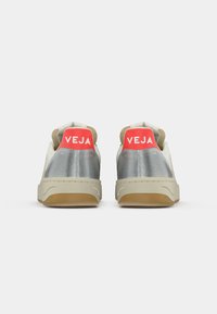 Pair of white sneakers with silver heel counters and red tabs labeled "VEJA" shown from the back on a white background.