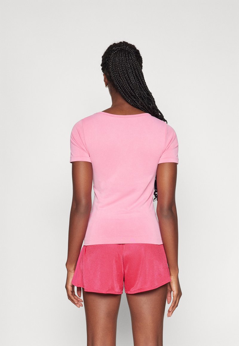 Top rosa aderente a maniche corte con scollatura rotonda abbinato a pantaloni corti rosa larghi, realizzati in un tessuto morbido e liscio.