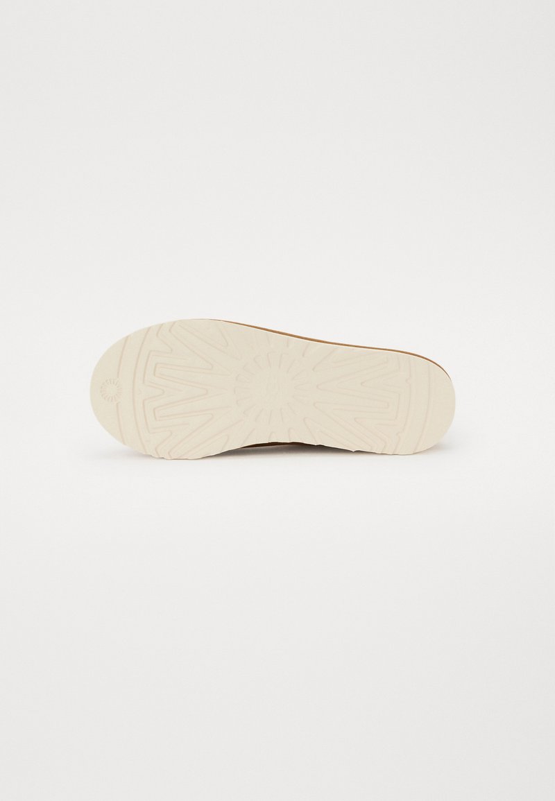 Suola della scarpa con un fondo in gomma beige chiaro e dalla texture. Presenta un motivo circolare e un design scanalato per una migliore aderenza. Bordo liscio.