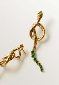 Pendientes en forma de serpiente dorada, con escamas texturizadas y una línea de piedras verdes a lo largo del cuerpo. Diseño de cierre de poste.