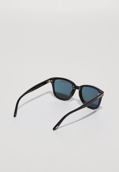 Black sunglasses with a geometric frame, dark blue lenses, glossy finish, thin black arms, and subtle metallic accents on the hinges.