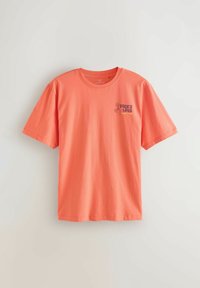 Koralfarvet T-shirt med korte ærmer, rund hals og lille "Picky bits Supper Club" tekst og grafik på venstre bryst.