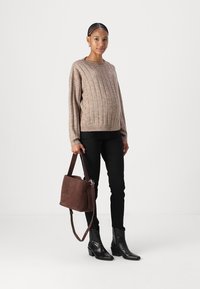 Beige bordázott pulcsi, fekete skinny nadrág, sötétbarna velúr táska pánttal, és fekete bokacsizma. Egyszerű, modern design és textúrált anyagok.