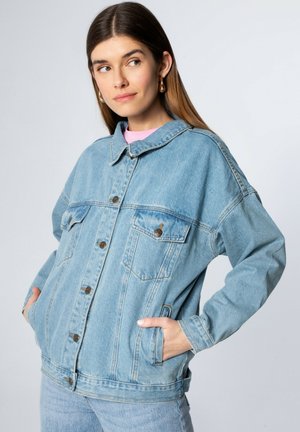 Lichtblauwe spijkerjack met een losse pasvorm, voorzien van knoopsluitingen, twee borstzakken en een puntkraag. Zachte textuur, casual ontwerp.