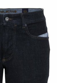 Jeans de mezclilla oscura con un corte recto, que presentan un diseño estándar de cinco bolsillos, costuras en contraste y un cierre de botón en la cintura.