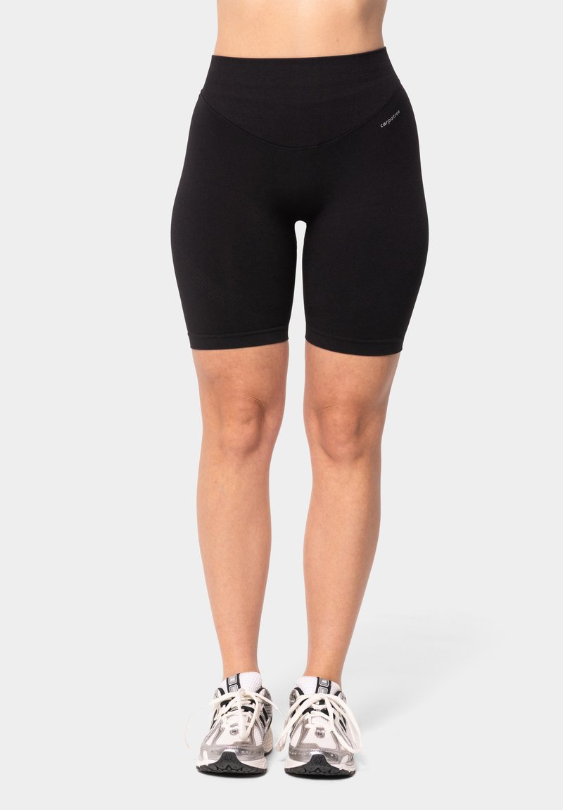 Pantaloni shorts da ciclismo neri a vita alta realizzati in tessuto elastico, con una texture morbida e una lunghezza corta, abbinati a sneakers grigie.