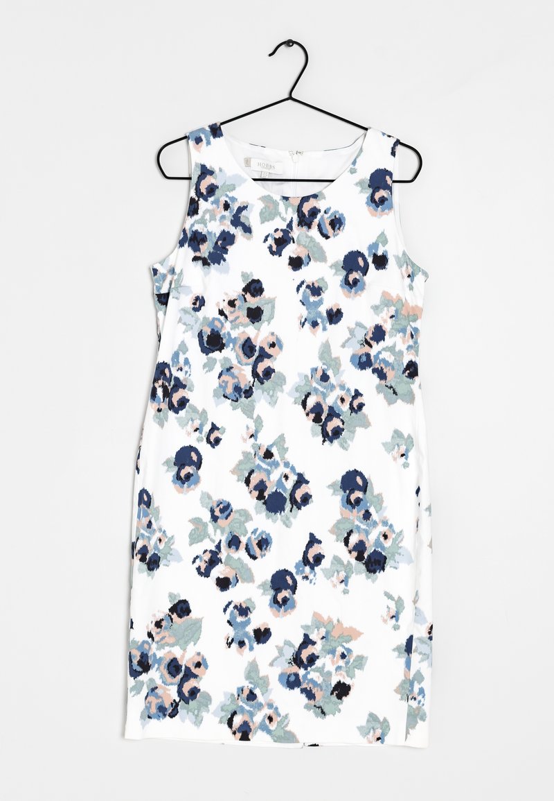 Ärmelloses weißes Kleid mit blauem und pinkem Blumenmuster, aufgehängt an einem schwarzen Kleiderbügel vor einem schlichten weißen Hintergrund.