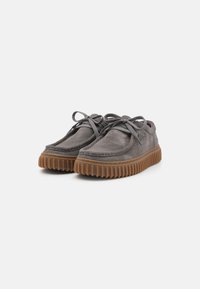 Gray suede shoes with a rounded toe, lace-up design, and rubber sole featuring a ribbed texture, highlighting durability and comfort.