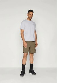 Šedé tričko s krátkým rukávem a logem, doplněné olivově zelenými šortkami. Černé ponožky a tenisky dotvářejí sportovní vzhled.