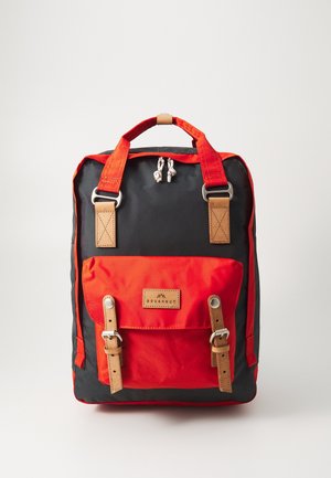 Sac à dos avec un corps noir, des accents rouge vif, des sangles en cuir, des éléments métalliques et une poche avant avec une fermeture à boucle.