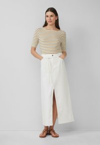 Haut en tricot rayé beige et blanc à manches courtes associé à une jupe maxi blanche taille haute en tissu texturé avec une fente devant et une ceinture.