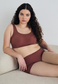 Brun sømløs BH og matchende shorts laget av mykt materiale. BH-en har en utringet hals og brede stropper for støtte.
