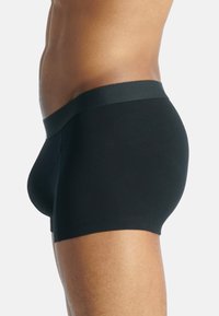 Sorte boksershorts laget av stretchy stoff, med en teksturert svart midjebånd. Passformen er tettsittende, som fremhever kroppens fasong.