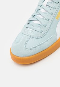 Sneaker azzurro chiaro con tomaia in suede e pelle, dettagli bianchi, lacci testurizzati e suola in gomma per una migliore aderenza.