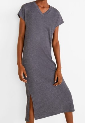 Szara dzianinowa sukienka midi bez rękawów z prążkowanym wzorem, dekoltem w serek i rozcięciem po boku, noszona przez osobę o ciemnym odcieniu skóry i złotej bransoletce na prawej ręce.