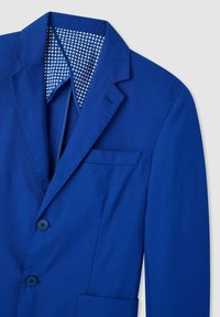 Blazer blu con tessuto texturizzato, rever a punta, due bottoni e una fodera interna a motivo nei toni del bianco e blu.