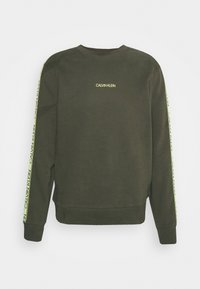 Sudadera verde oscura con cuello redondo, que presenta un pequeño logotipo amarillo en el pecho y franjas amarillas en contraste a lo largo de las mangas.