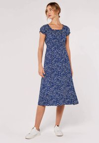 Blå blommig klänning med korta, puffiga ärmar och fyrkantig halsringning. Tillverkad av lättviktigt tyg, med en åtsittande bodice och flödande kjol.