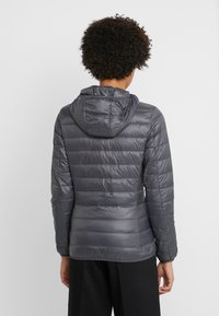 Chaqueta aislante gris con diseño acolchado, capucha, mangas largas y textura suave, vista desde atrás sobre un fondo blanco.