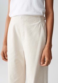 Helle korduroyhose mit gerippter Textur, ausgestattet mit einem elastischen Bund und Seitentaschen, auf Oberschenkelhöhe präsentiert.
