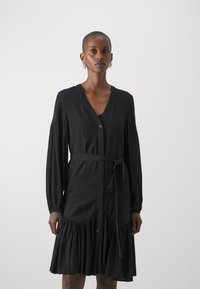 Black dress featuring a V-neck, long sleeves, and a tie belt. The design includes a ruffled skirt and buttons down the front. Smooth texture.
