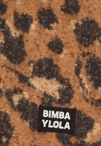 Tkanina w panterkę w odcieniach brązu i czerni o miękkiej fakturze; zawiera czarną metkę z napisem "BIMBA YLOLA" w białych literach.