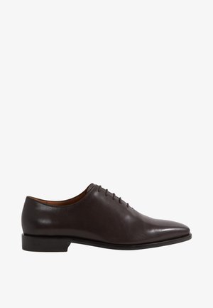 Zapato Oxford de hombre de cuero marrón oscuro con cordones cerrados, tacón bajo y puntera puntiaguda, mostrado desde el lado interior sobre fondo blanco.