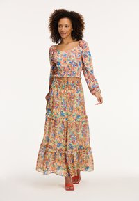 Virágmintás cropped top és réteges maxi szoknya szett élénk színekben. Hosszú ujjaival, rugalmas derékpántjával, folyékony anyagával és réteges kialakításával rendelkezik.